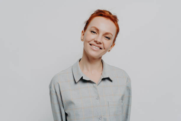 istock Cheerful beautiful red haired woman with beaming smile posing isolated on grey studio background 1336930633