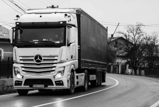 remorque mercedes benz actros dans la circulation, sur route goudronnée. photo noir et blanc avec camion mercedes. targoviste, roumanie, 2020. - tirgoviste photos et images de collection