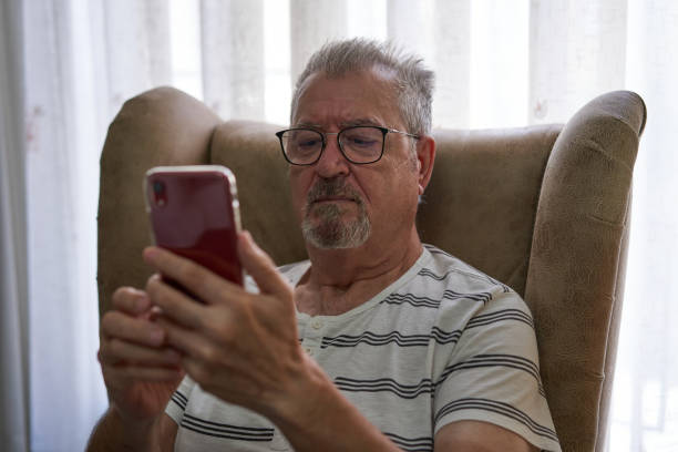 istock Older man is sitting in an armchair using his smart phone. 1336933951