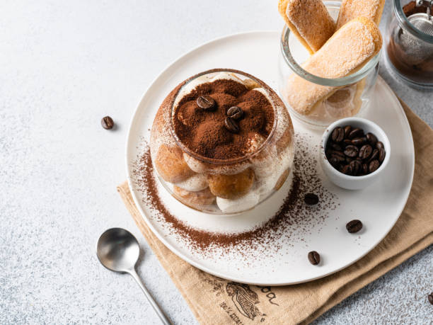 Tiramisu cake in glass. Cocoa powder and coffee beans decoration. Copy space. Closeup view. Traditional italian dessert made of lady fingers cookies soaked in coffee and mascarpone cheese cream tiramisu glass stock pictures, royalty-free photos & images
