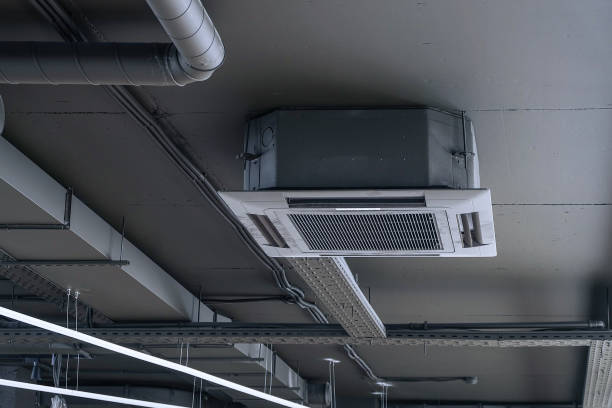 istock Cassette split system on gray ceiling with ventilation ducts. Indoor unit of air conditioner. Engineering air system. 1336937333