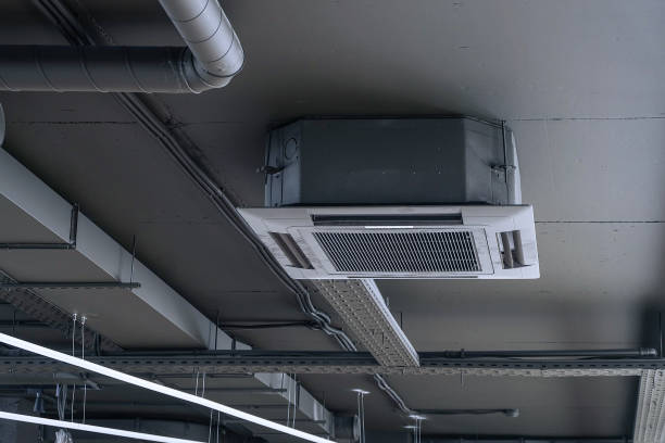 Cassette split system on gray ceiling with ventilation ducts. Indoor unit of air conditioner. Engineering air system. stock photo