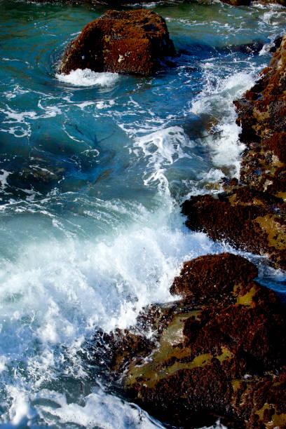 istock looking down cliff onto turquoise waves splashing onto rocky coastline 1336944929