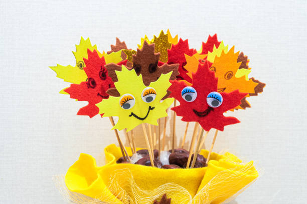 Red, brown, orange, goldy and yellow autumn soft cloth artificial leaves with face on sticks stock photo