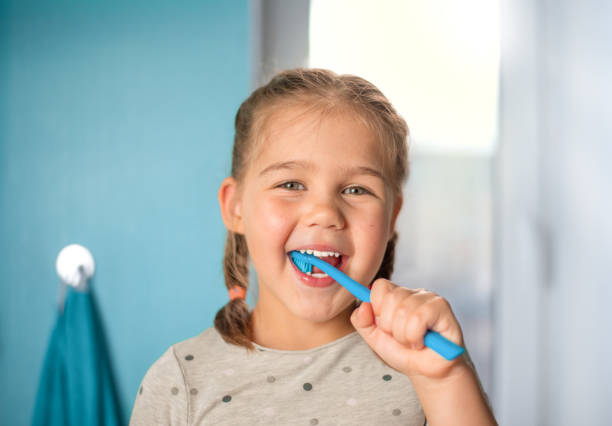 маленькая девочка чистит зубы в ванной комнате - dental hygiene human teeth toothbrush brushing teeth стоковые фото и изображения