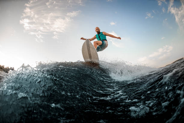 istock Active adult man wakesurfing on the board down the river 1336949310