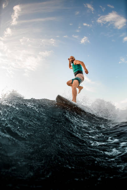 istock sportive man standing on one leg on a wakeboard and riding a wave 1336949364