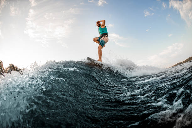 istock man having fun and standing on one leg on a wakeboard and riding a wave 1336949397