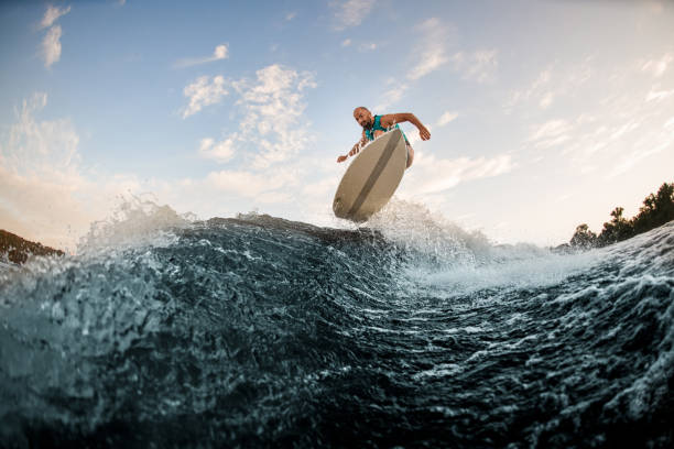 istock Energy man effectively jumps on wakeboard over splashing wave. Wakesurfing on the river. 1336951031