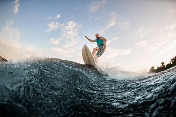 istock athletic guy having fun and wakesurfing on the board down the river 1336951930