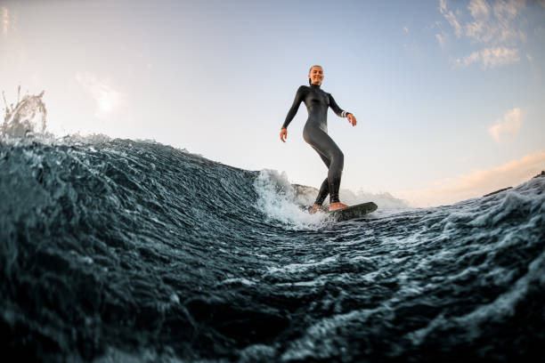 jovem mulher bonita acordar no tabuleiro descendo o rio contra o fundo do céu azul - surfe - fotografias e filmes do acervo