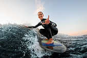 istock smiling woman sits on wakesurf board and rides the wave and touches the waves with one hand 1336953432