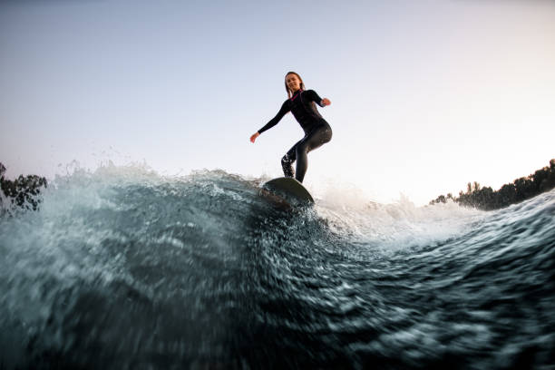 istock athletic female wakesurfer balanced on the board on river wave 1336954065