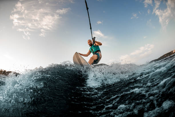 man holds rope and catches a wave on wakesurf. Wakesurfing on the river. stock photo