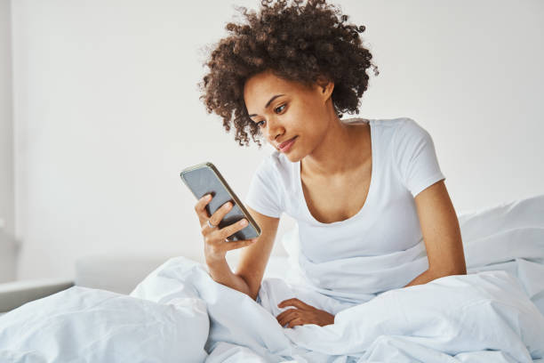 istock Female with a smartphone in her hand sitting in bed 1336962127