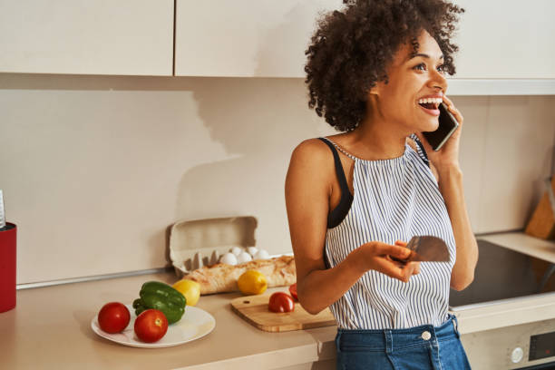 istock Joyful lady having a phone conversation in the kitchen 1336962188