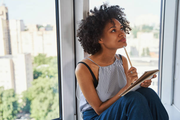 istock Pensive pretty woman leaned back against the window pondering over something 1336966312