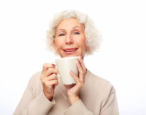 istock old excited lady smiling laughing, holding cup drinking coffee or tea 1336971635