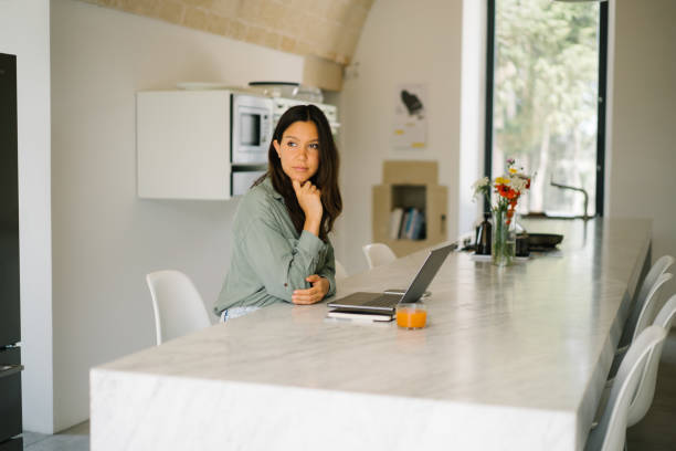 istock Young woman works on a computer in a naturally lit kitchen 1336974131