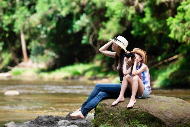 istock Mother and daughter using binoculars on mountain stream rocks 1336980490