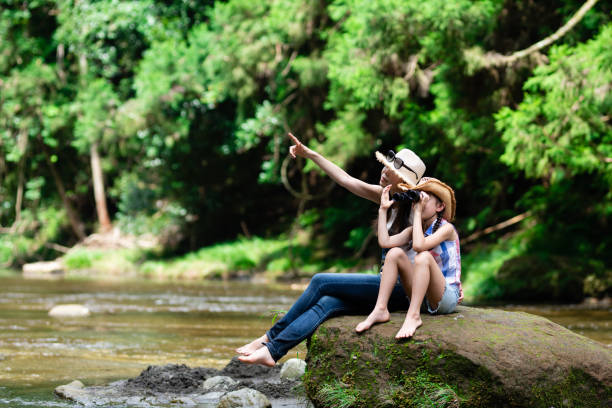 istock Mother and daughter using binoculars on mountain stream rocks 1336980509