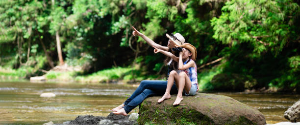 istock Mother and daughter using binoculars on mountain stream rocks 1336980512