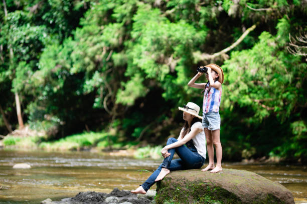 istock Mother and daughter using binoculars on mountain stream rocks 1336980514