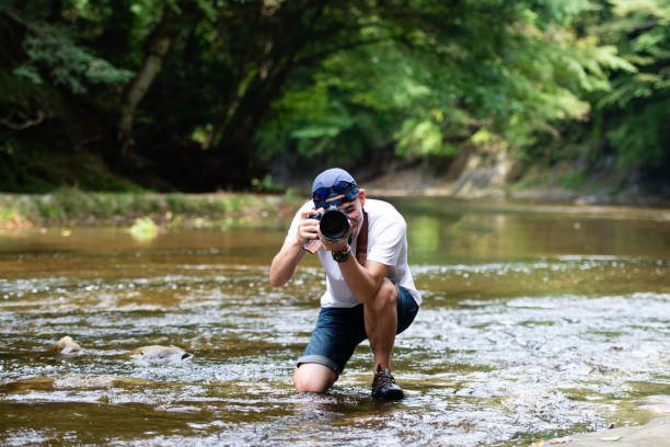 istock A man holding a single-lens reflex camera in a mountain stream 1336980660