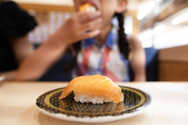 サケ寿司を食べる子供 - 回転寿司 ストックフォトと画像