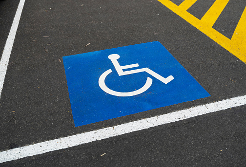 A person holding the disability sign with the sculpture of Themis the Greek goddess of justice