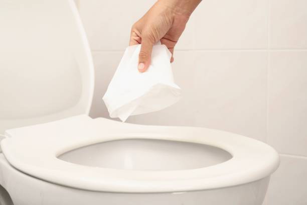Disposing of toilet paper in the toilet stock photo