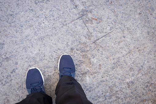 Selfie of feet with shoes on concrete floor.