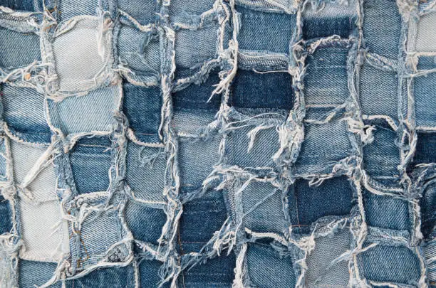 Surface of pieces of old tattered denim closeup