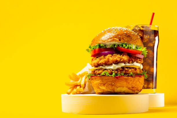 вкусный гамбургер с колой и картофелем фри на желтом фоне - potato patties стоковые фото и изображения
