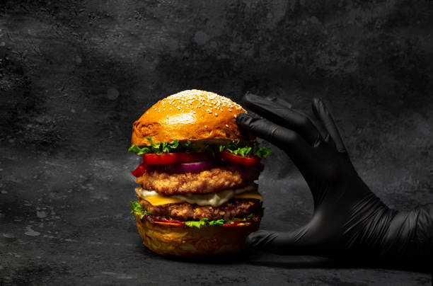 istock Hand grabbing a big double chicken burger with cheese and vegetables 1336993606