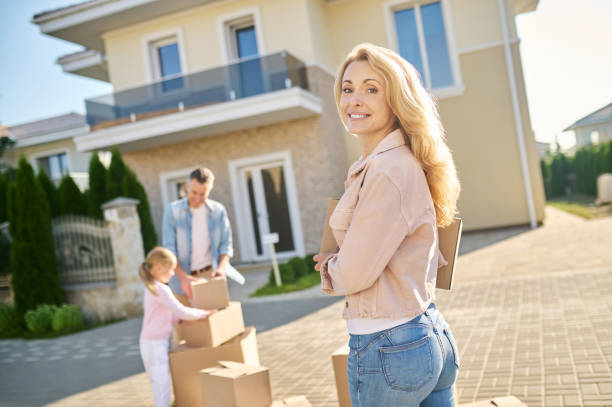 istock Woman with box walking to house looking back 1337001400