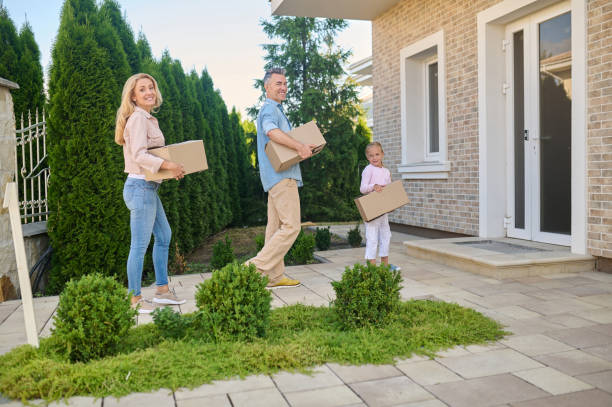 istock Mom, dad and daughter carry boxes into house 1337001437