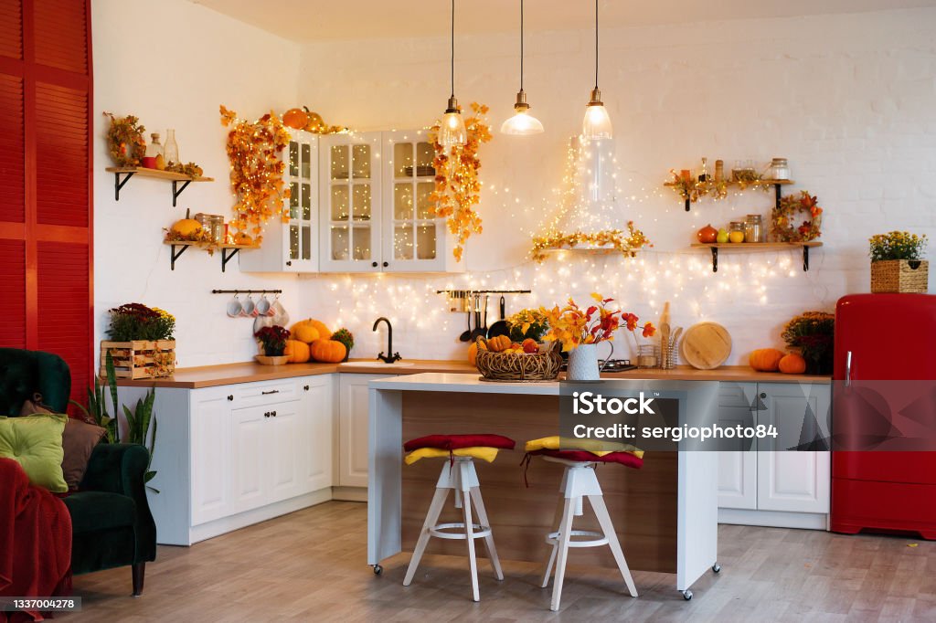 Autumn kitchen interior. Red and yellow leaves and flowers in the vase and pumpkin on light background Autumn kitchen interior. Red and yellow leaves and flowers in the vase and pumpkin on white background. Autumn Stock Photo