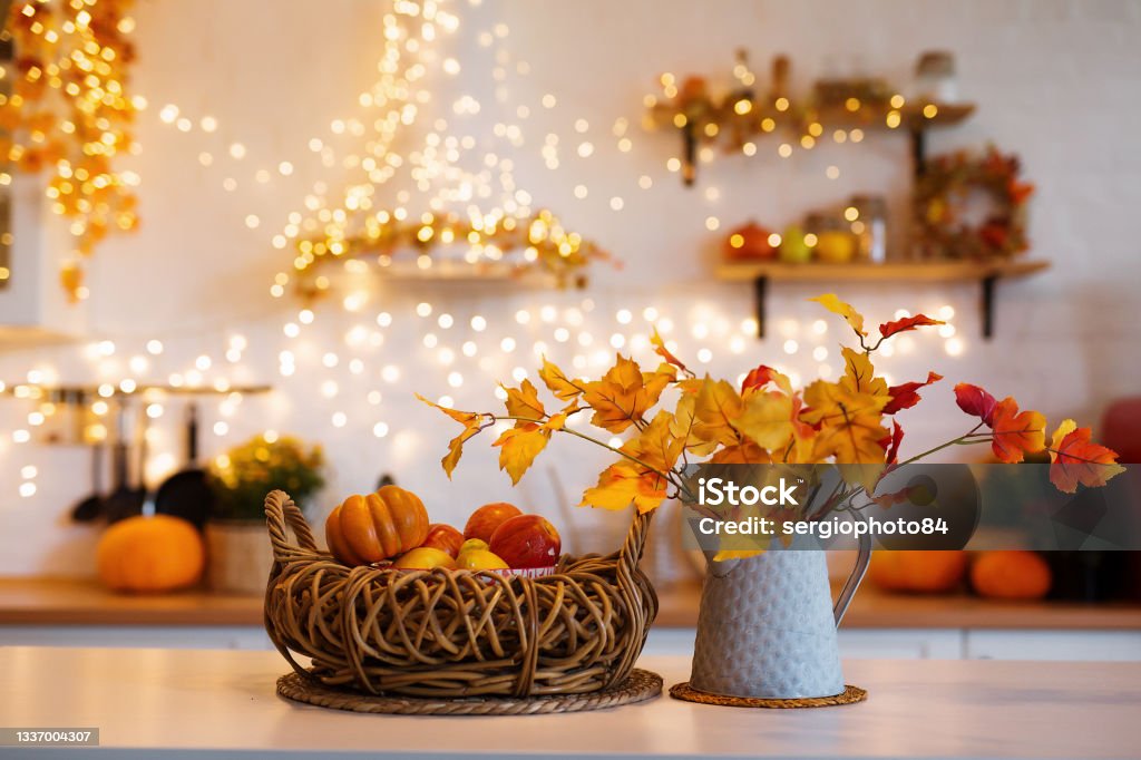 Autumn kitchen interior. Red and yellow leaves and flowers in the vase and pumpkin on light background Autumn kitchen interior. Red and yellow leaves and flowers in the vase and pumpkin on white background. Autumn Stock Photo