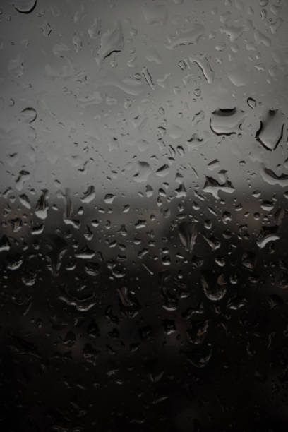 Drops of rain on a black dramatic window glass background. Autunm Rain, depression concept image\