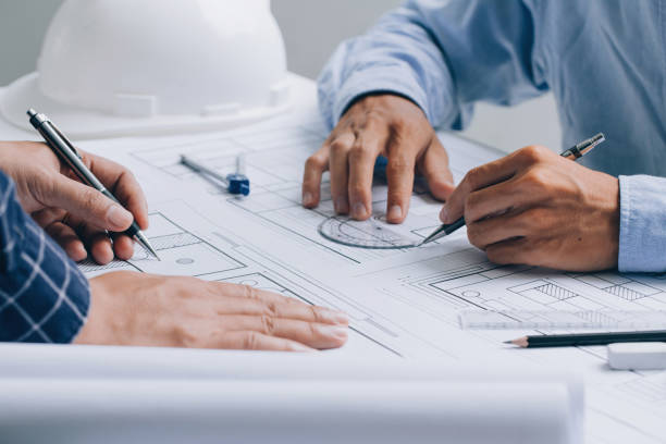 istock Two Architect discussing a project and working on blueprint at the construction site at desk in the office, Architectural and engineering concept. 1337012824