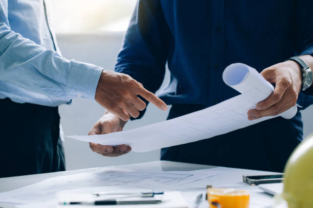 Engineer Teamwork Meeting, Engineers discussing on a project and working on blueprint meeting for project working with a partner at the construction site at desk in the office, Construction concept. Engineer Teamwork Meeting, Engineers discussing on a project and working on blueprint meeting for project working with a partner at the construction site at desk in the office, Construction concept. civil engineer stock pictures, royalty-free photos & images