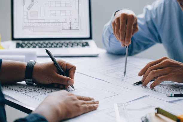 istock architect drawing on a blueprint on architectural project at the construction site at office desk in the office.Architectural and engineering concept. 1337013777