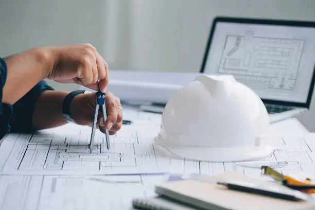 Photo of Architect man sketching architectural project on blueprint, Architectural/engineering concept