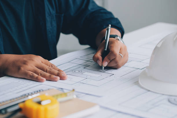 istock architect drawing on a blueprint on architectural project at the construction site at office desk in the office.Architectural and engineering concept. 1337014023