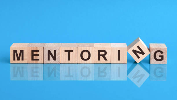 palavra de mentoria é feita de blocos de construção de madeira deitados sobre a mesa amarela, conceito - mentor - fotografias e filmes do acervo