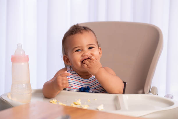 Adorable baby eating food by himself. stock photo