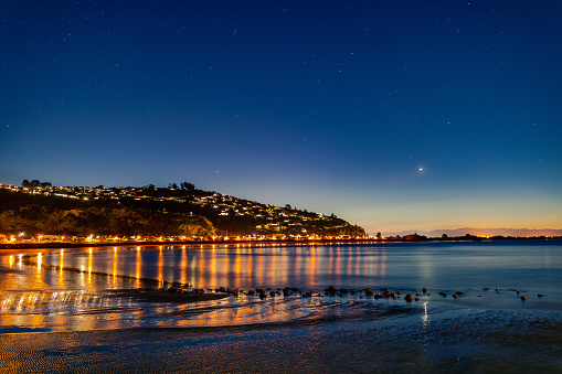 This July 2021 dusk long-exposure image shows Sumner Beach in Ōtautahi Christchurch, Aotearoa New Zealand. This single frame captures the stars that were visible on a clear winter night in the seaside community. This is a 25-second exposure.