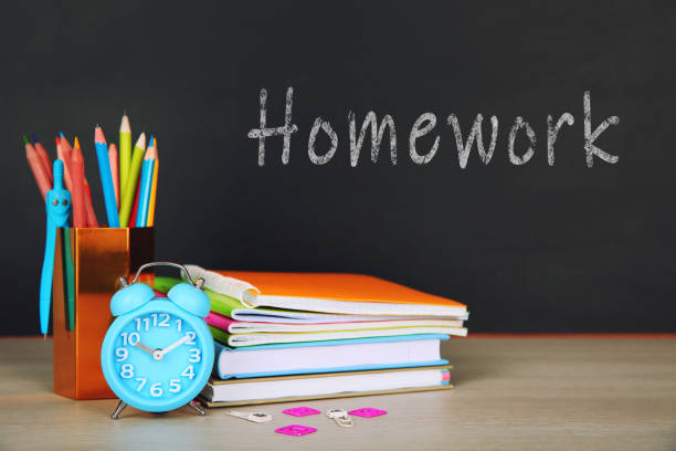 istock Composition with stationery and alarm clock on table near blackboard. Doing homework 1337017404