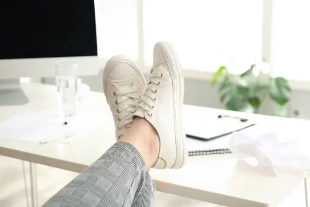 Photo of Lazy overweight worker with feet on desk in office, closeup